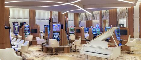 Un lobby de hotel lujoso con un piano de cola, asientos cómodos y varias máquinas de juego.