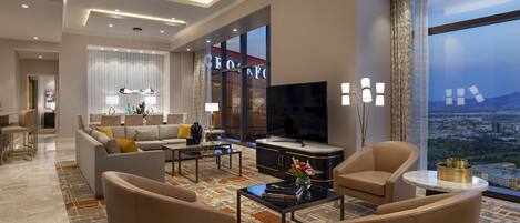 A modern living room with a sofa, armchairs, a coffee table, and a TV.