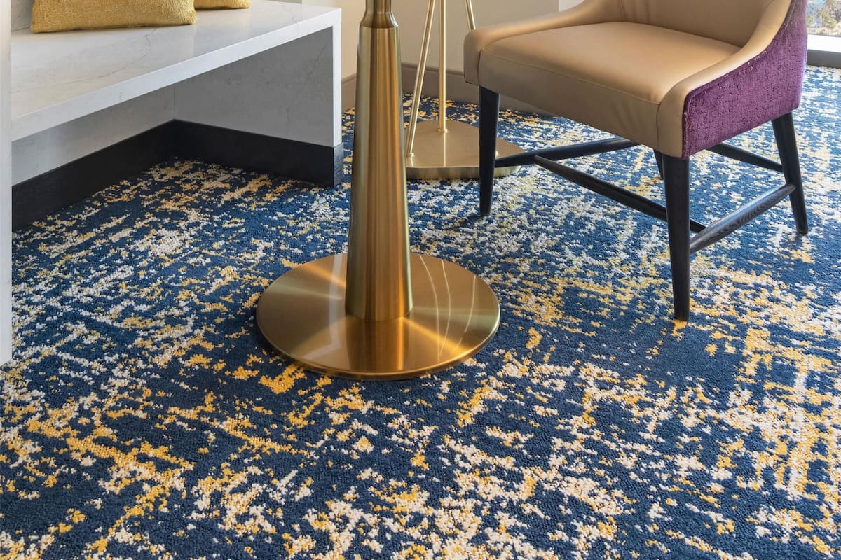 Una habitación de hotel con una mesa redonda, un sofá, una silla y una lámpara de pie.