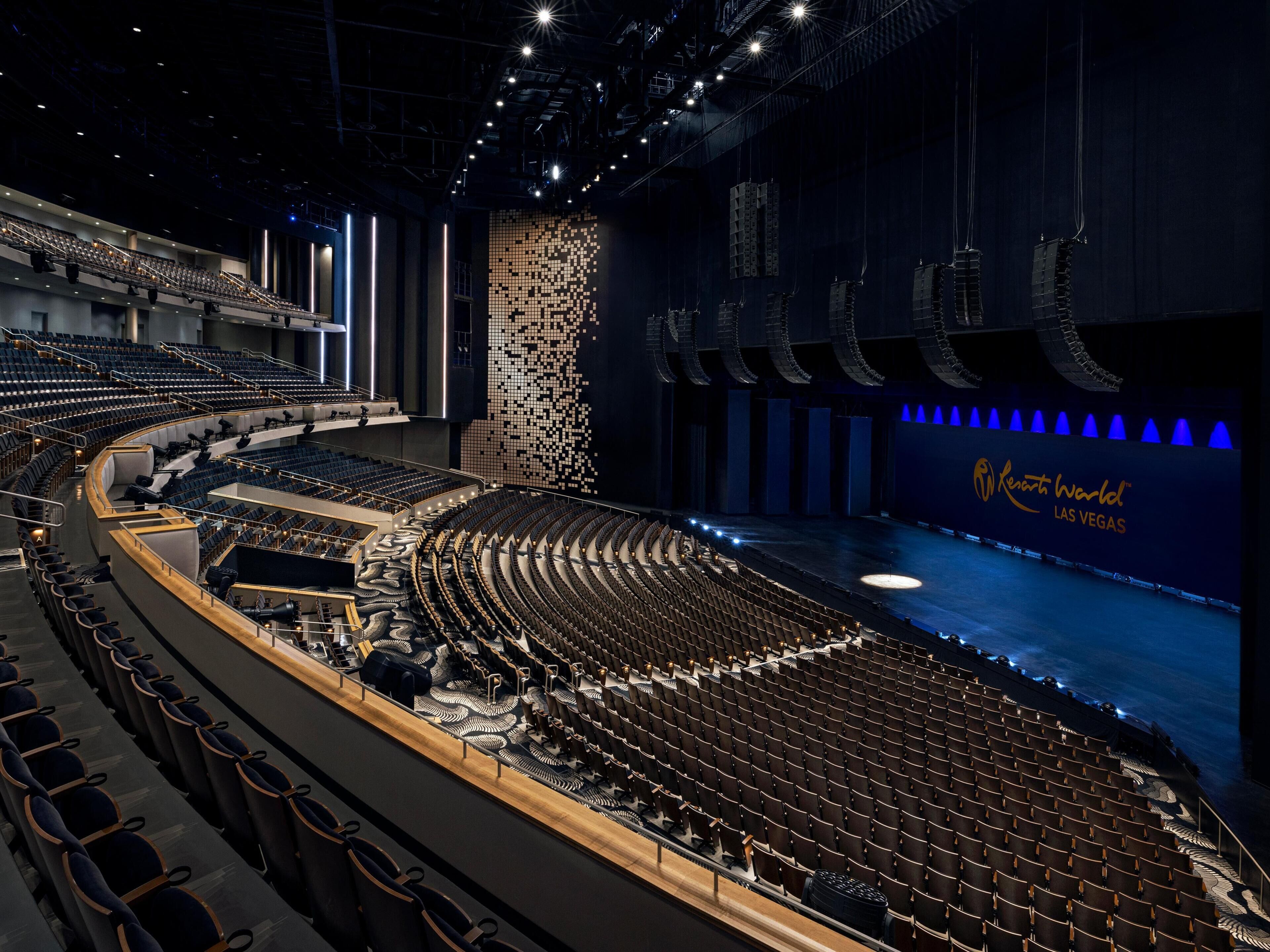 Ein großes, modernes Auditorium mit abgestuften Sitzreihen und einer Bühne.
