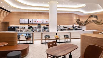 A modern cafe with a central counter, seating area, and a decorative wall mural.