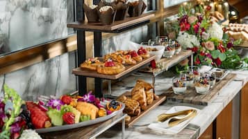 Un buffet proposant une variété de viennoiseries, de fruits et de desserts.