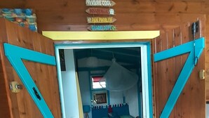 A room with a bed, a window, and a door with a sign above it. - "LE TI-COLIBRI" CHARMING BUNGALOW at the foot of "La Soufrière" volcano (Saint-Claude)