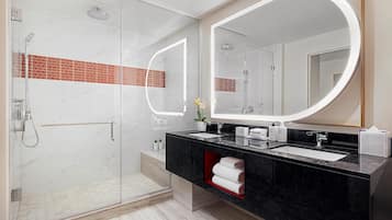 A modern bathroom with a glass shower enclosure, a black marble sink, and a large mirror.