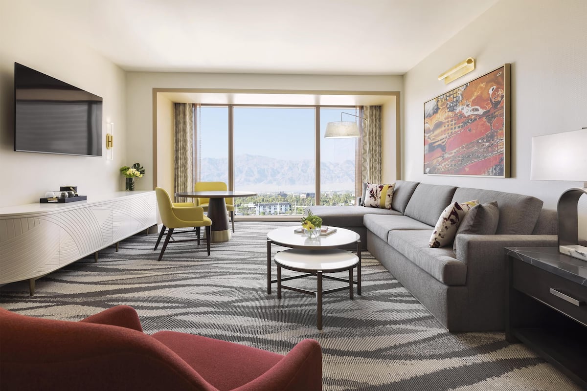 A modern living room with a sofa, a coffee table, and a TV mounted on the wall.