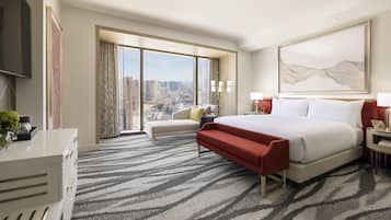 A hotel room with a large bed, a sofa, a desk, and a view of the city.