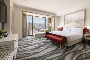 Habitación de hotel con una cama grande, un sofá, un escritorio y vistas a la ciudad.