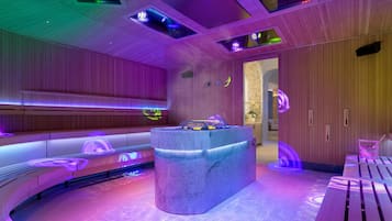 Un espacio de spa moderno con un mostrador de recepción de mármol central, paneles de madera y una zona de estar circular con un banco de madera.