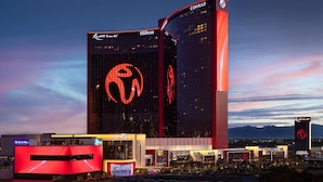 A modern hotel with a prominent logo, multiple floors, and a well-lit facade.