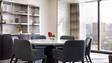 Een moderne eetruimte met een ronde tafel, zes stoelen en een grote boekenkast.