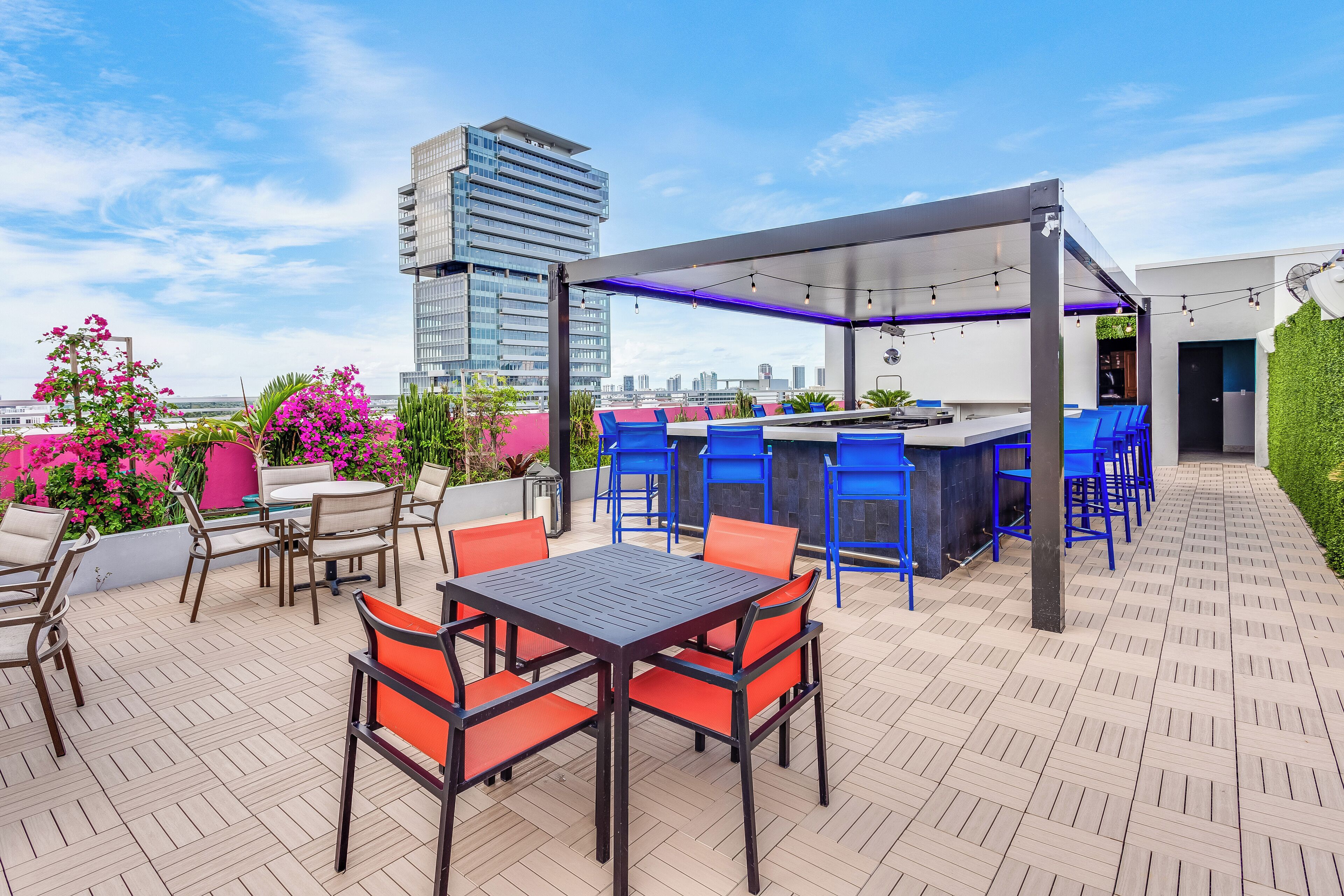 An outdoor patio with a bar area, seating, and a view of a cityscape.