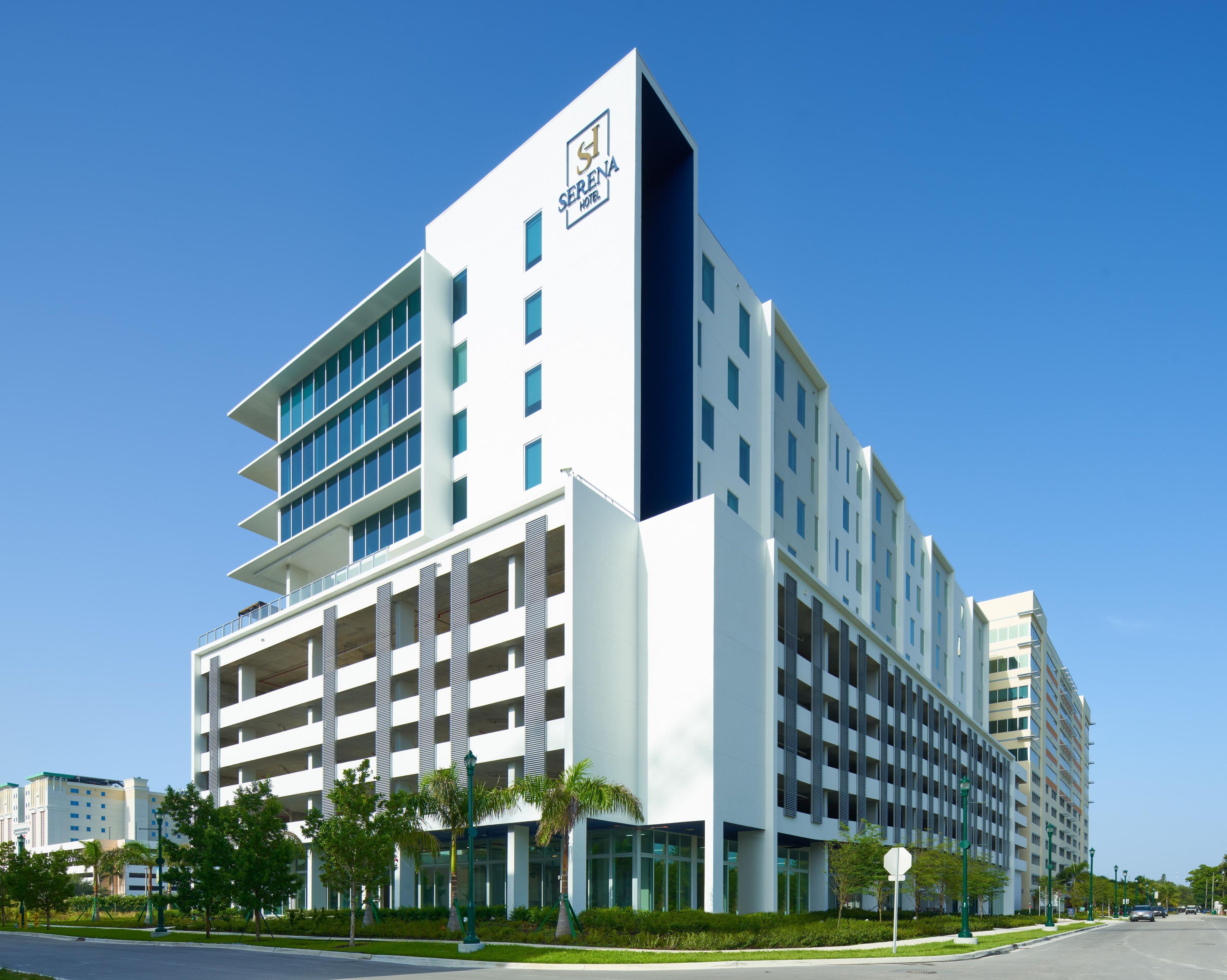 A modern hotel with a prominent logo, multiple floors, and a parking garage.