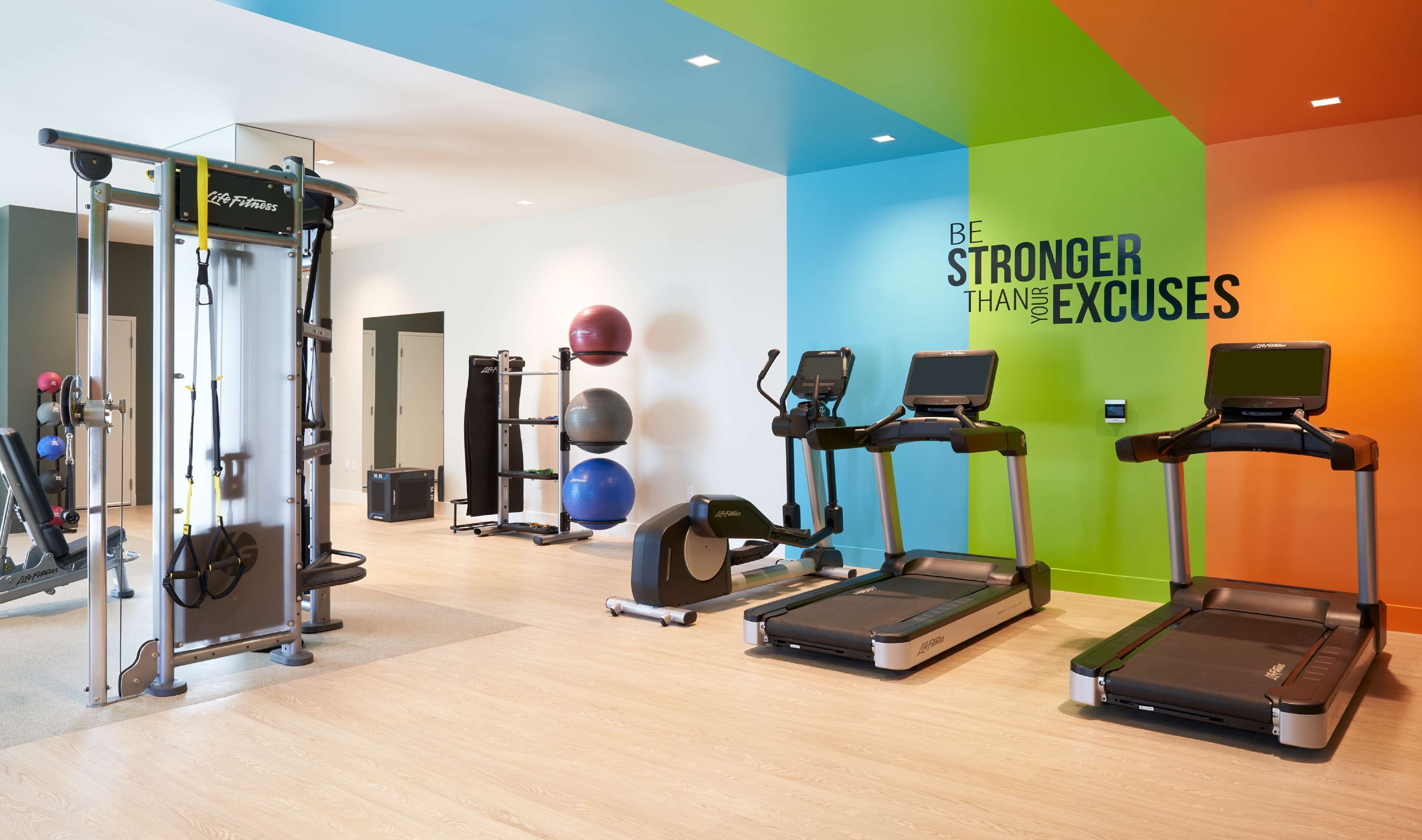 A modern gym with treadmills, a weight machine, and exercise balls.