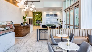 A modern lobby with a reception desk, seating area, and a green wall with plants. - SERENA Hotel Aventura Miami, Tapestry Collection by Hilton (Aventura)