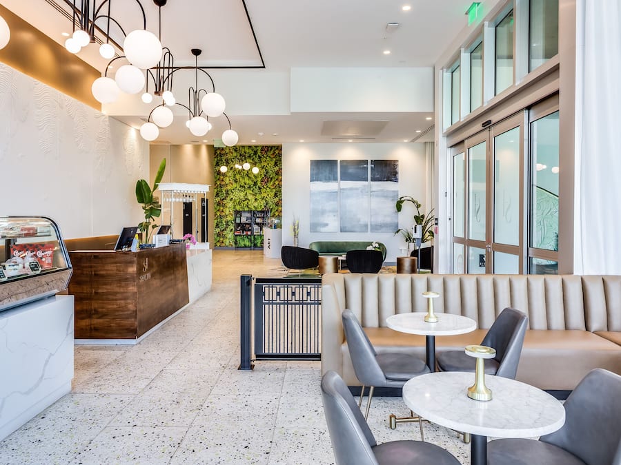 A modern lobby with a reception desk, seating area, and a green wall with plants.