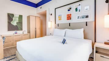 Ett hotellrum med en stor säng, en garderob i trä, ett skrivbord med en lampa och en vägg med inramade tavlor.
