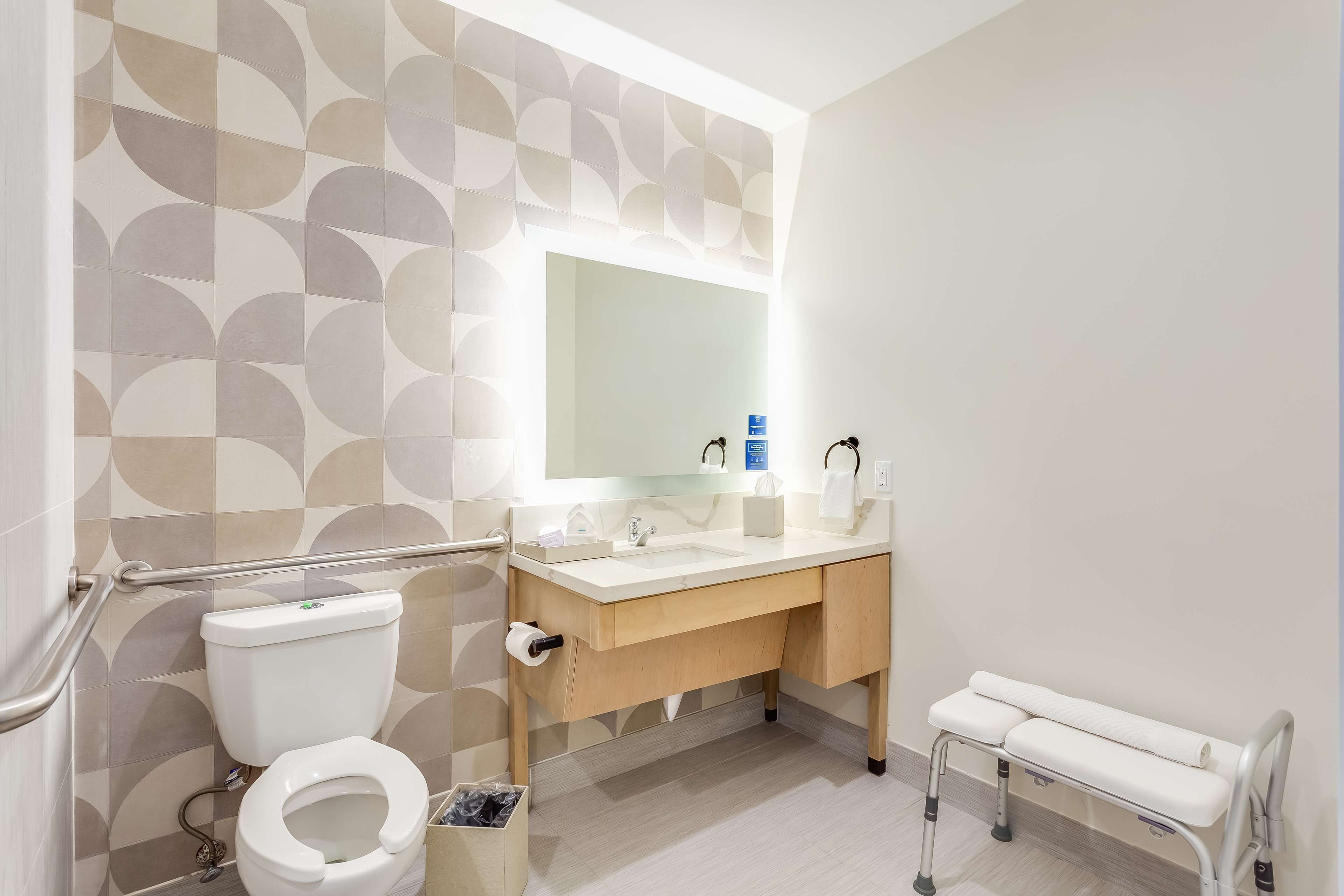 A modern bathroom with a toilet, sink, and bench.