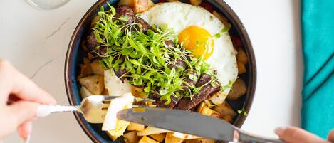 Un plato de comida con un huevo frito, verduras y patatas.