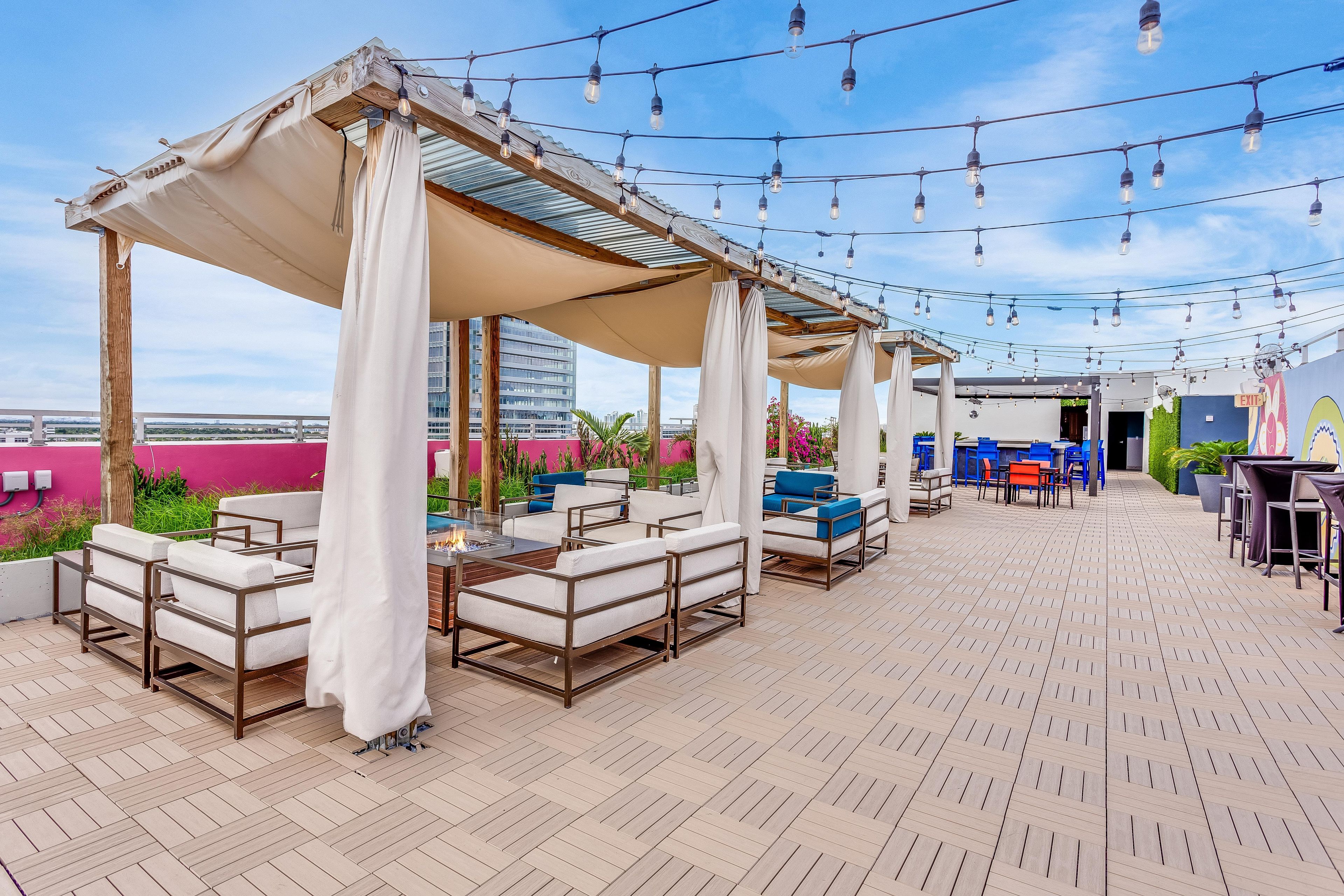 An outdoor seating area with tables and chairs, a pergola structure, and string lights.