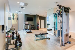 Une salle de sport équipée de machines de musculation, de tapis de course et d’un banc.