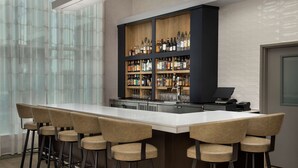 A modern bar area with a long counter, multiple stools, and a well-stocked liquor cabinet.