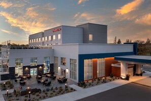 A modern hotel with a patio area featuring outdoor seating and a fire pit.