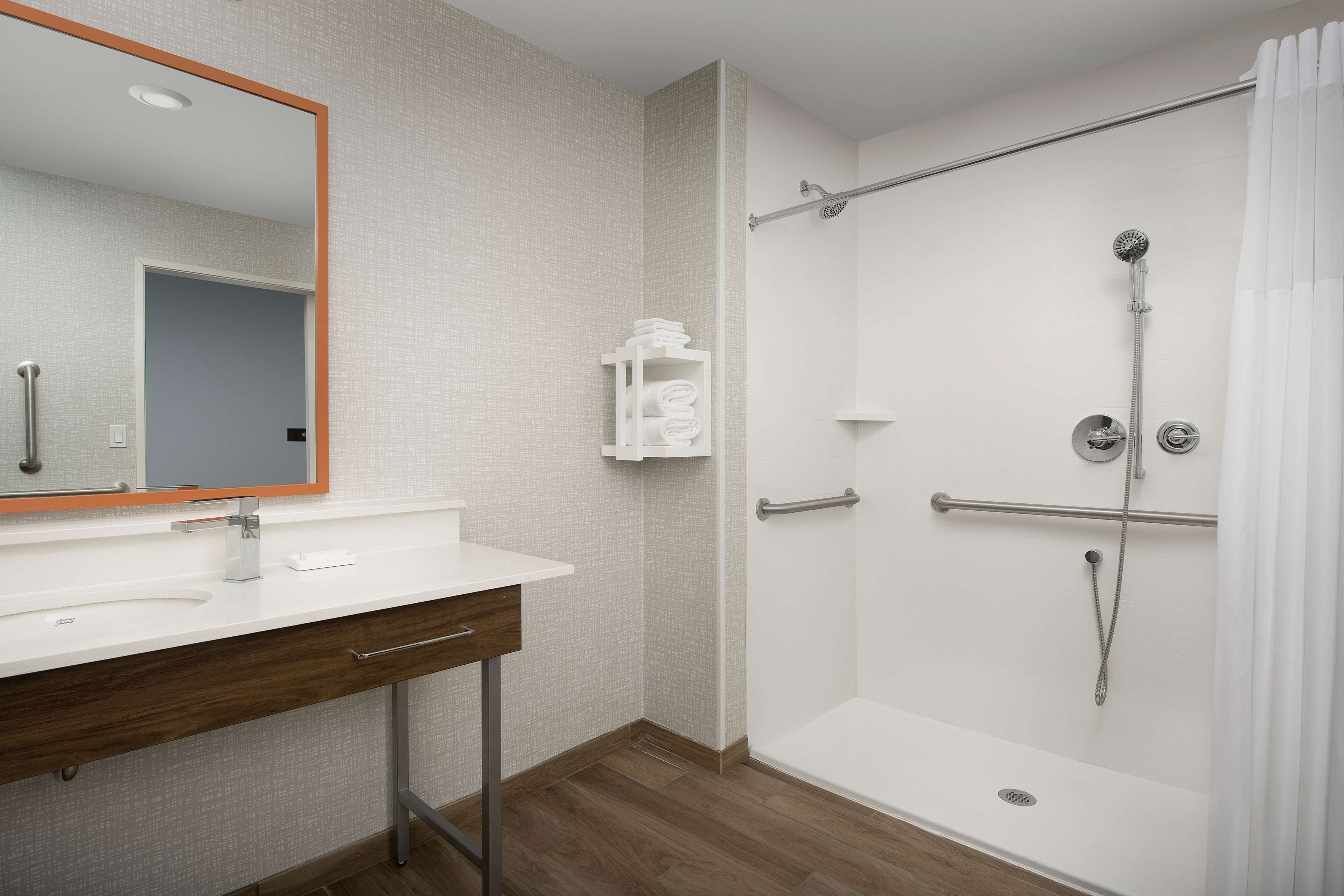 Une salle de bain moderne avec un lavabo blanc, un miroir et une douche.