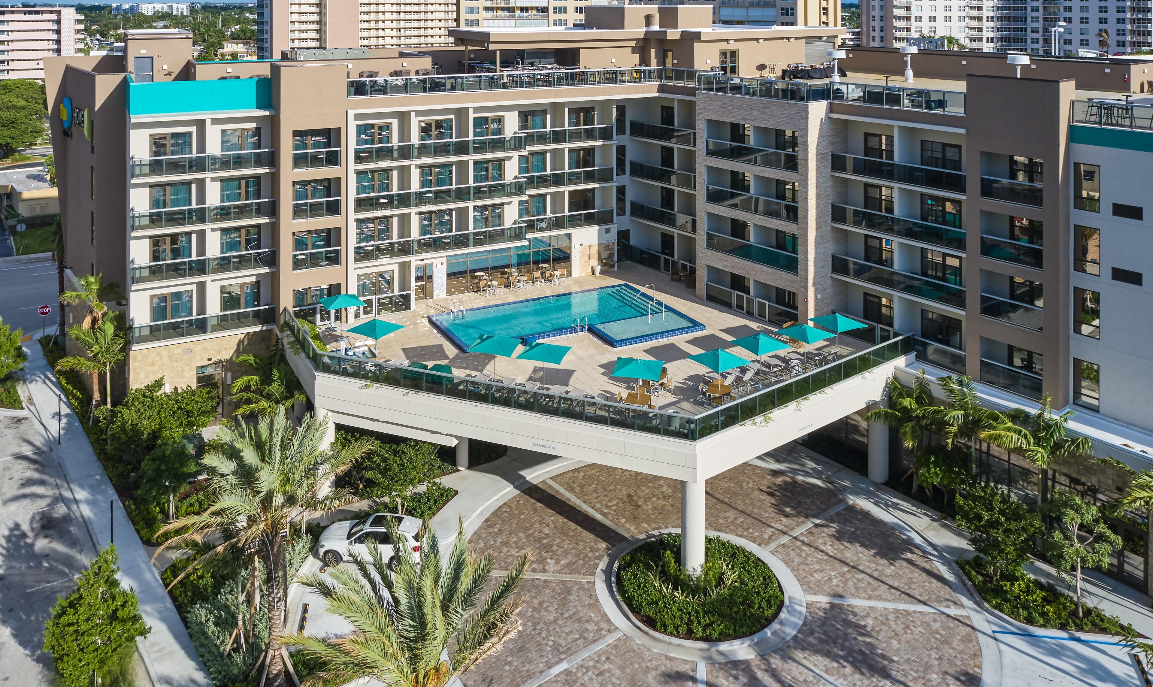 A multi-story hotel with a rooftop pool, outdoor seating, and a landscaped courtyard.