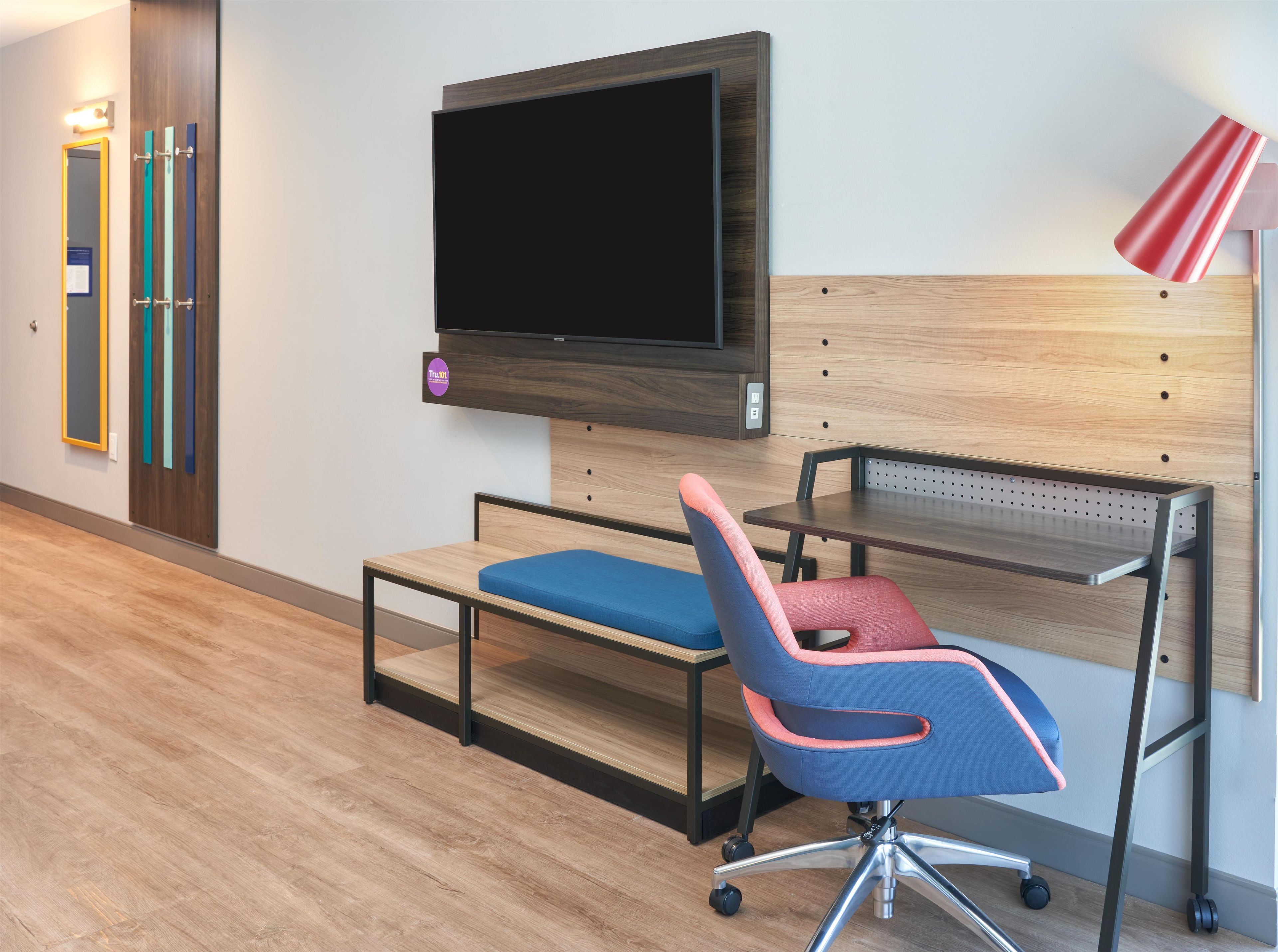 Un espacio de oficina moderno con un escritorio, una silla y un televisor de pantalla plana montado.