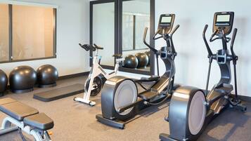 A home gym with stationary bikes, a rowing machine, and exercise balls.