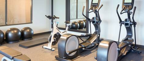 A home gym with stationary bikes, a rowing machine, and exercise balls.