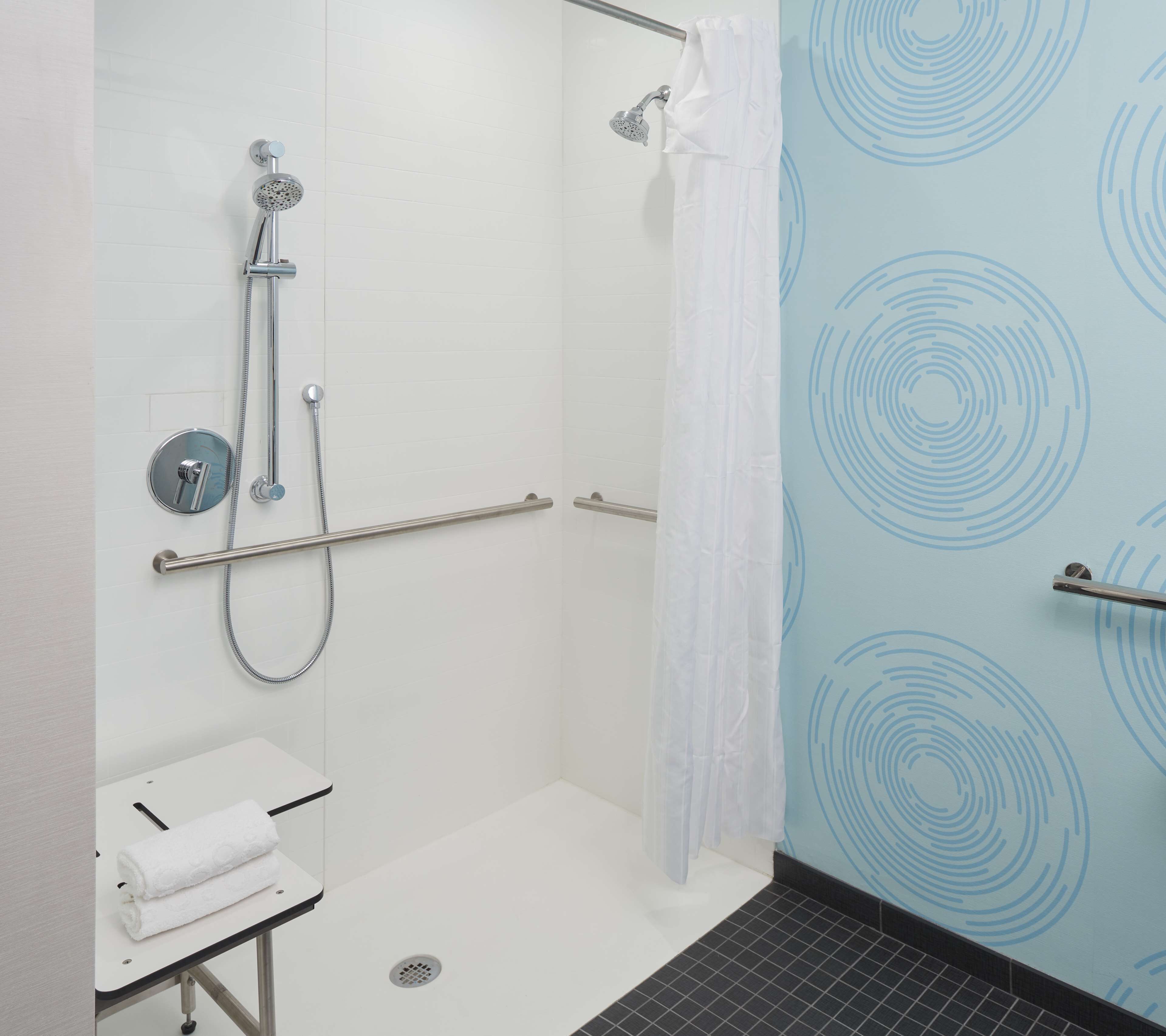A shower with a handheld showerhead, a handheld shower attachment, and a wall-mounted showerhead.