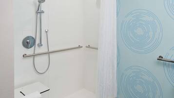 A shower with a handheld showerhead, a handheld shower attachment, and a wall-mounted showerhead.