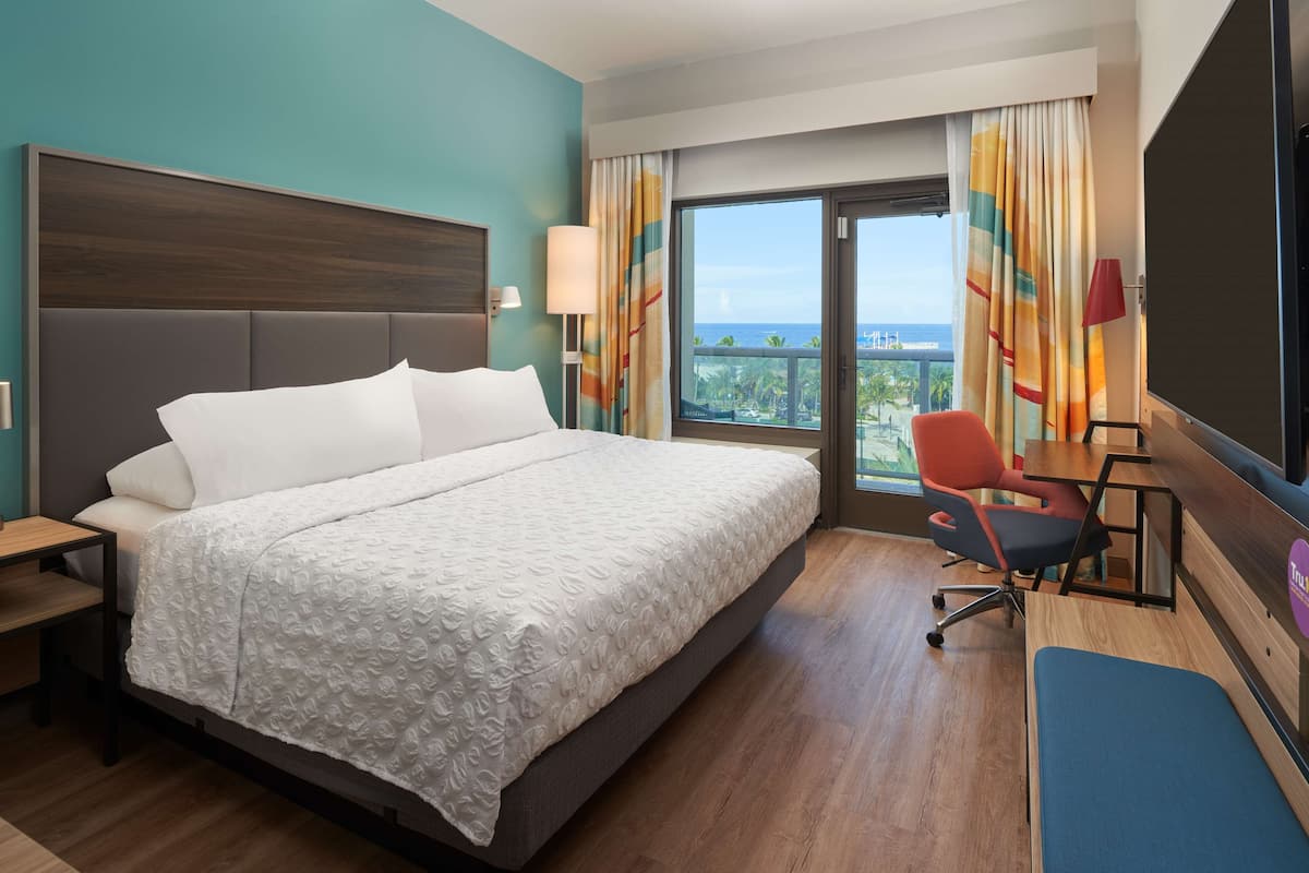 A hotel room with a large bed, a desk, a chair, and a TV.