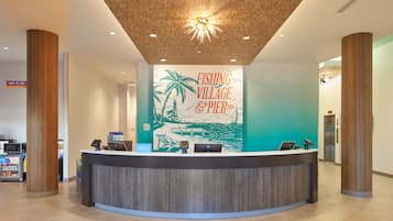 A reception desk with a wooden ceiling and a mural depicting a beach scene.