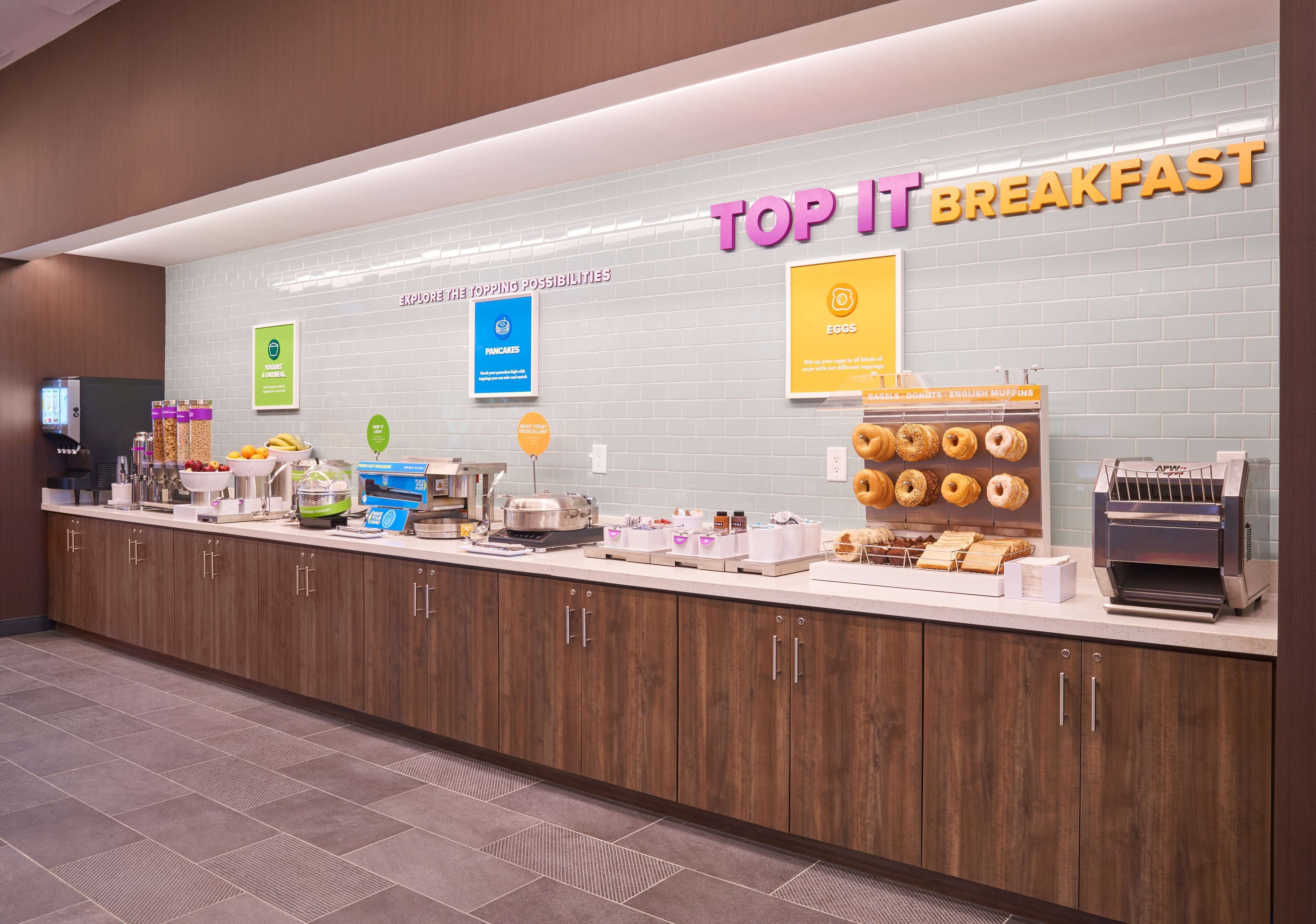 Una barra de desayuno con un letrero que dice "TOP IT BREAKFAST" y varios alimentos exhibidos.