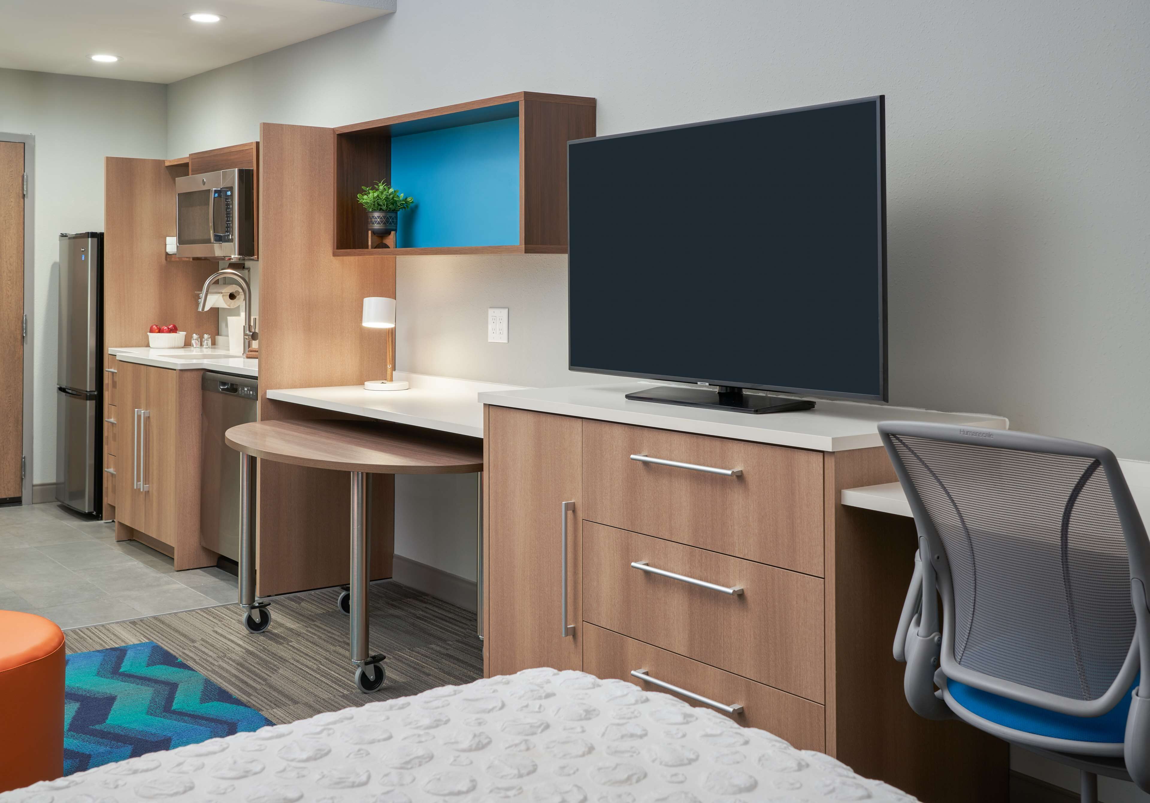 A modern kitchen with a microwave, refrigerator, and a small plant on the countertop.