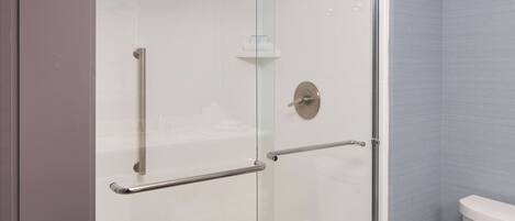 Een moderne badkamer met een douchecabine van glas, een toilet en een handgreep.
