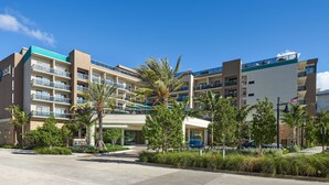 Ein mehrstöckiges Hotel mit Balkonen, Palmen und blauem Himmel.