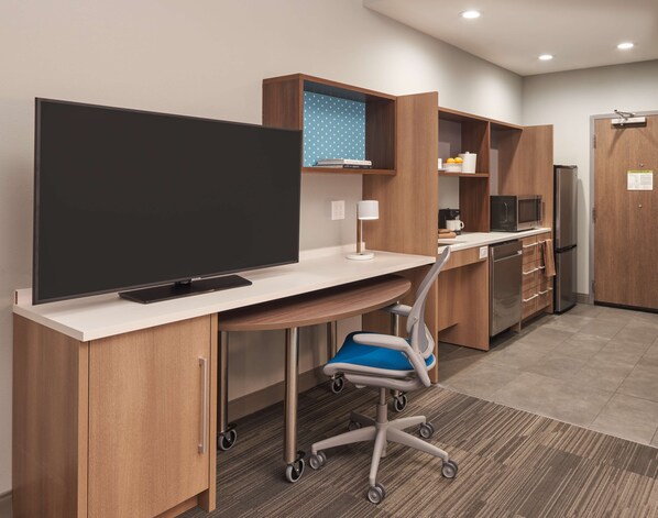 A modern kitchenette with a flat-screen TV, a microwave, and a refrigerator. - Home2 Suites by Hilton Pompano Beach Pier (Pompano Beach)