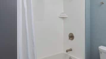 A modern bathroom with a bathtub, shower, and toilet.