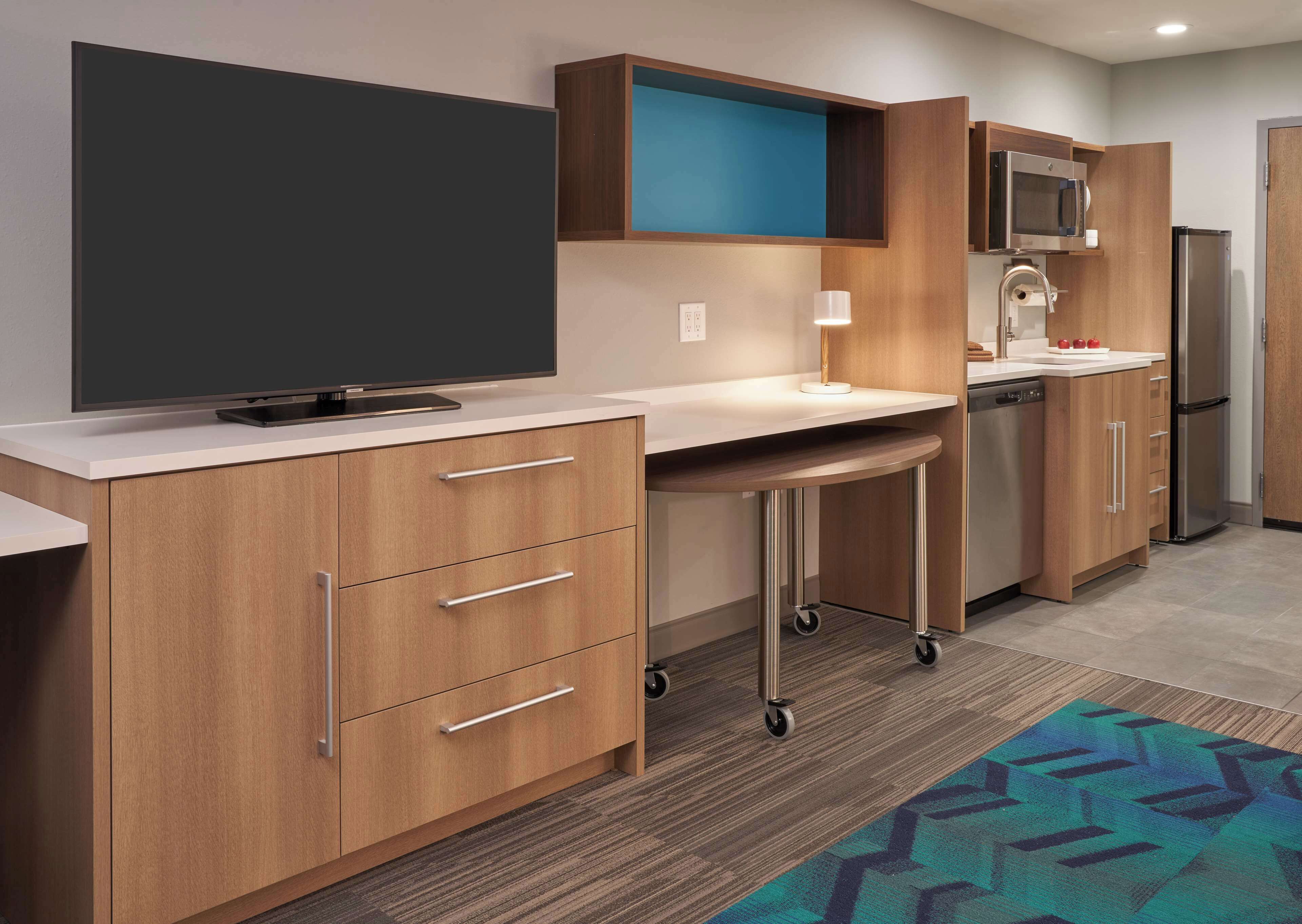 A modern kitchen with a flat-screen TV, microwave, and refrigerator.