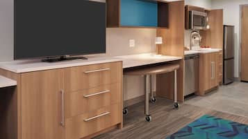 A modern kitchen with a flat-screen TV, microwave, and refrigerator.