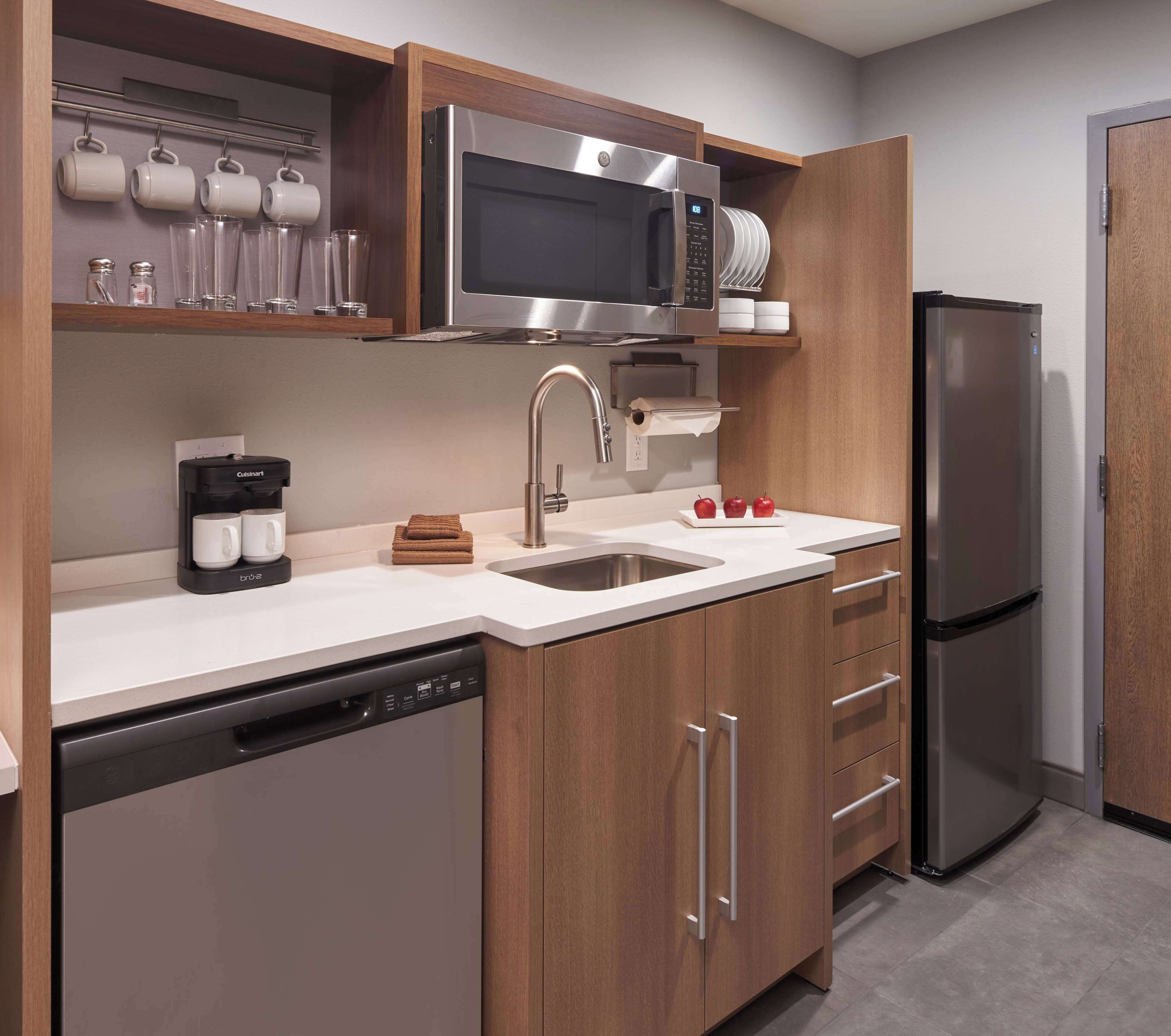 A modern kitchen with stainless steel appliances, wooden cabinets, and a dishwasher.
