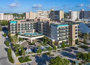 A modern hotel with multiple floors, a rooftop pool, and a parking area. - Home2 Suites by Hilton Pompano Beach Pier (Pompano Beach)