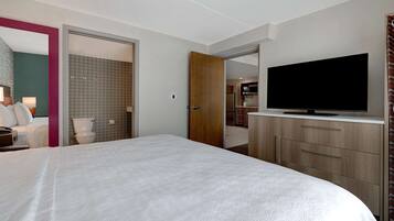 A hotel room with a large bed, a television on a wooden cabinet, and a bathroom visible through an open door.