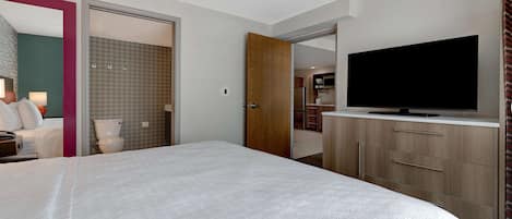 A hotel room with a large bed, a television on a wooden cabinet, and a bathroom visible through an open door.