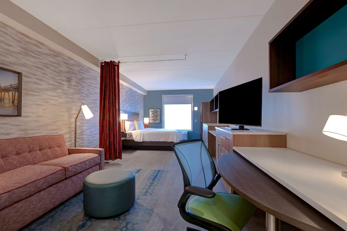 Ett hotellrum med en soffa, ett skrivbord, en stol, en säng och en tv.