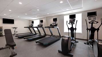 A gym with treadmills, elliptical machines, and a bench.