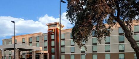 A hotel with a modern design, featuring a prominent entrance with a covered area and a sign that reads "HOME".